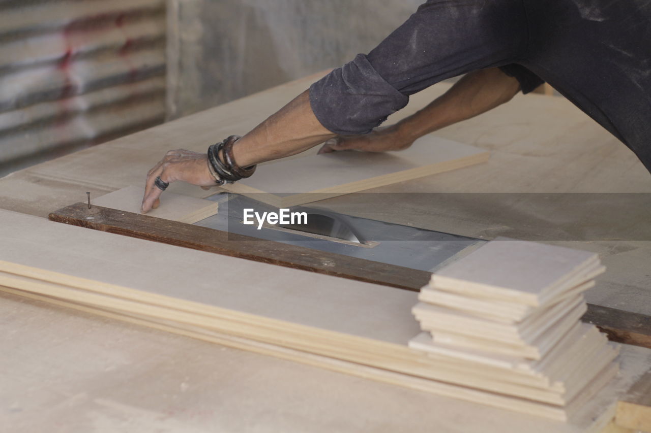 MIDSECTION OF PERSON WORKING ON WOOD AT HOME