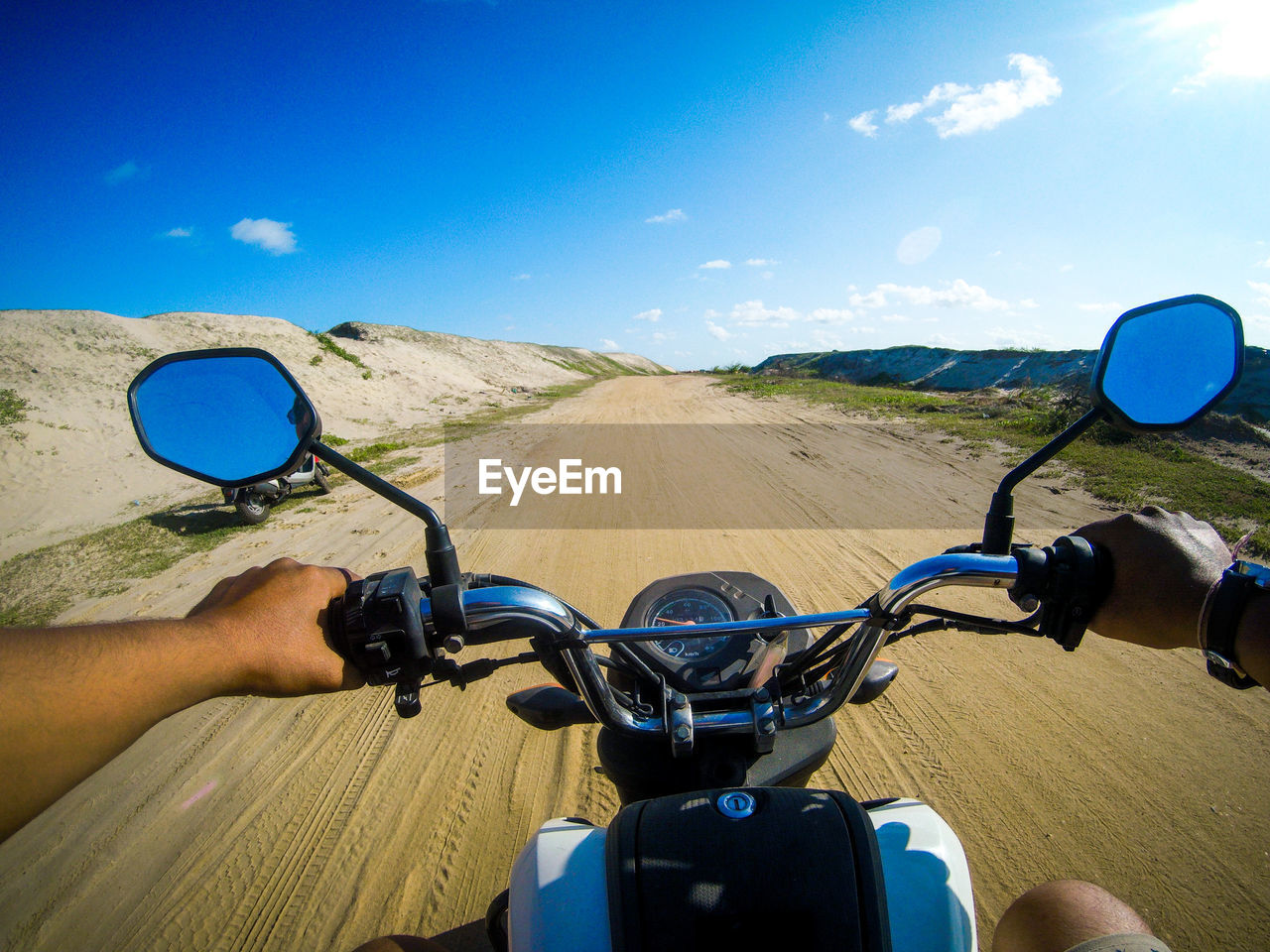 Cropped image of man riding motorcycle on dirt road