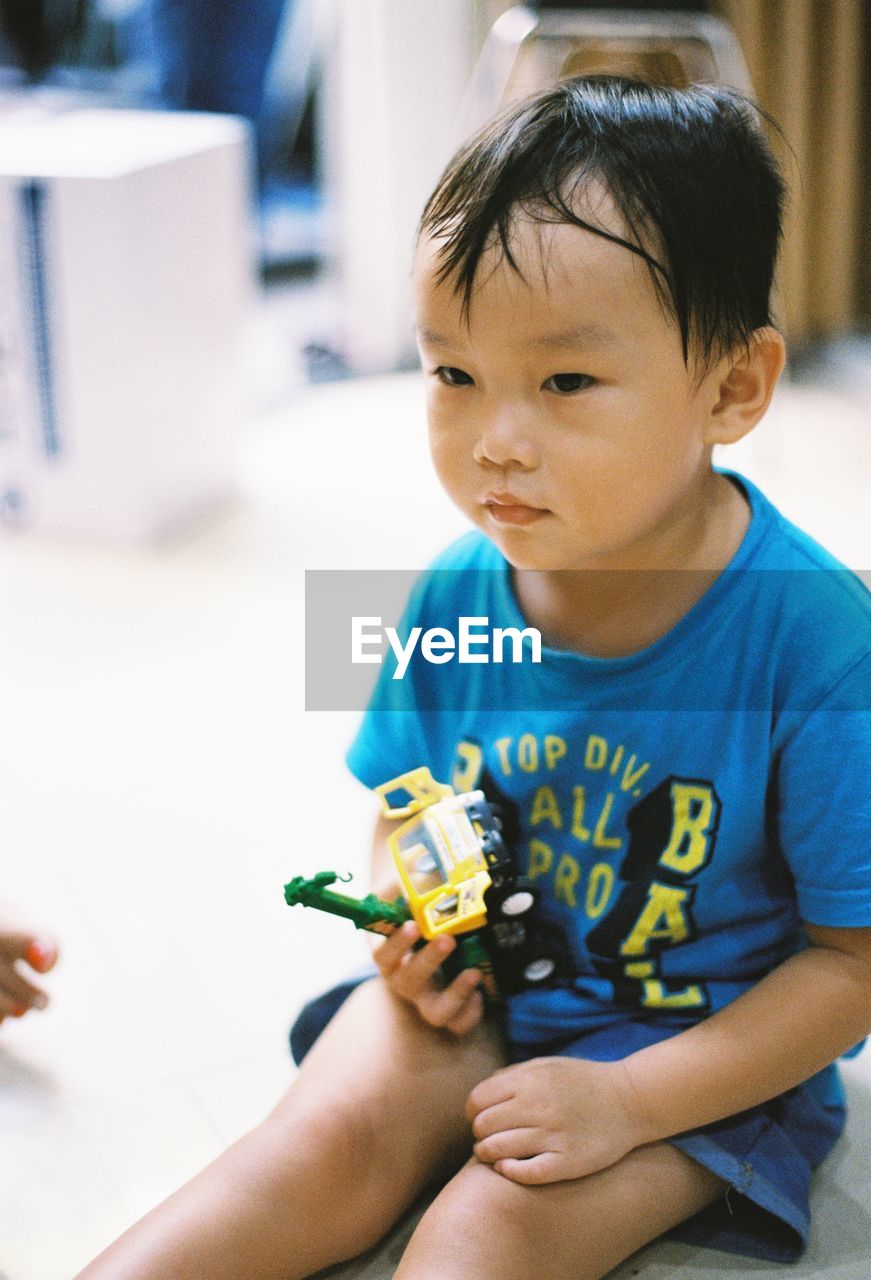 Boy holding toy car while sitting at home