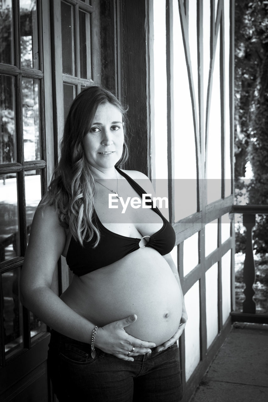 Seven months pregnant young woman dressed in black bikini and jeans