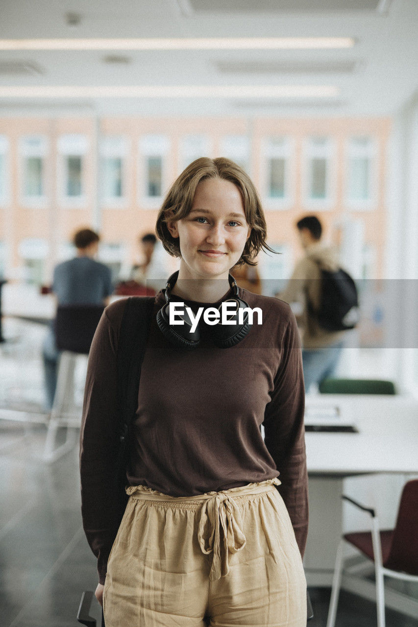 Portrait of smiling female student standing in university