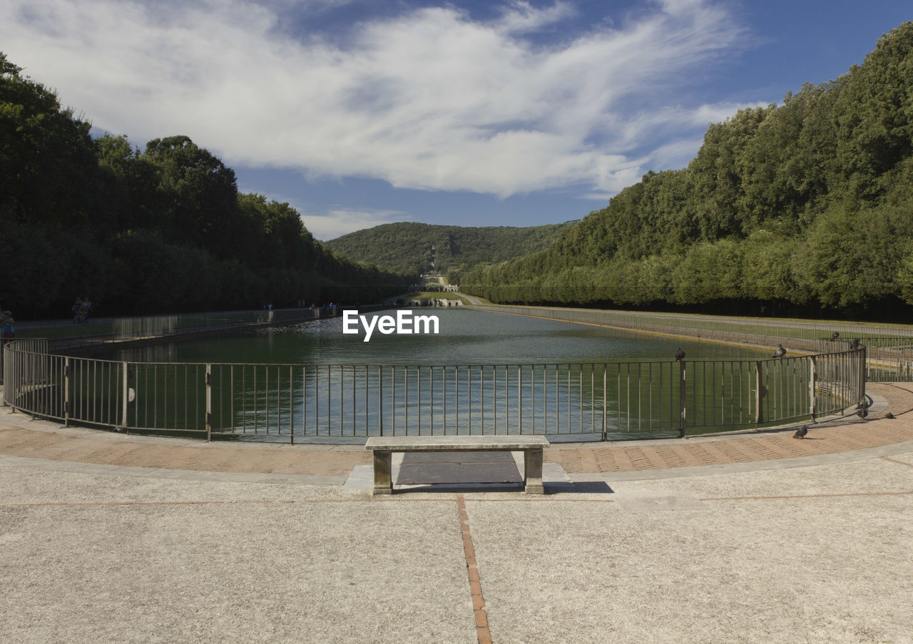 Empty swimming pool by lake against sky