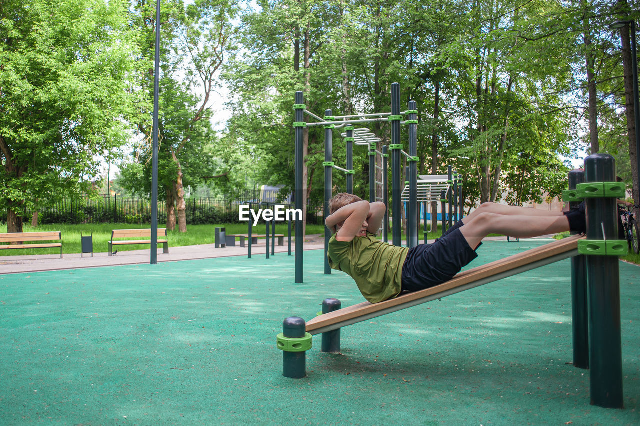 rear view of man sitting on slide at park