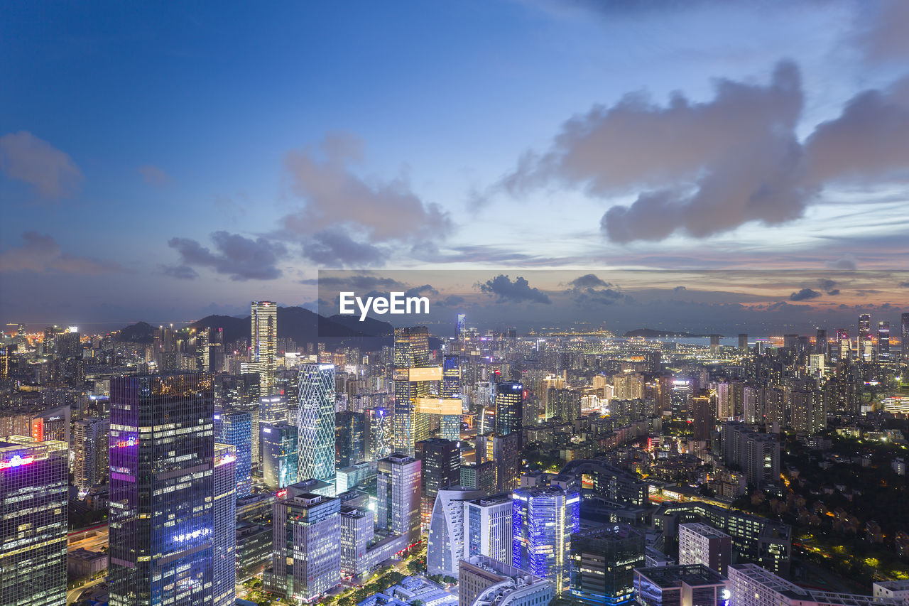 HIGH ANGLE VIEW OF ILLUMINATED CITY AGAINST SKY