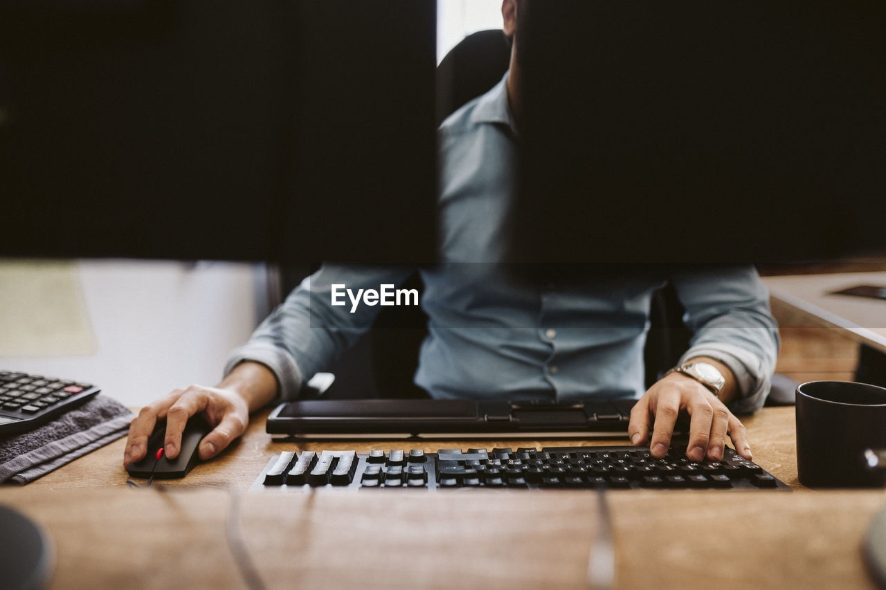 Businessman using computer while sitting at desk in office