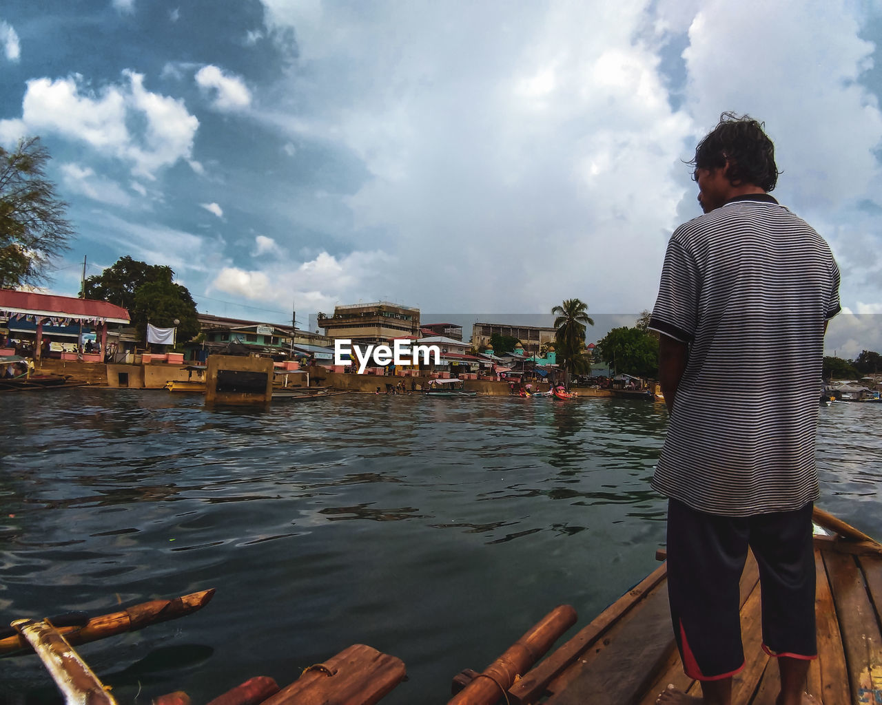 REAR VIEW OF MAN STANDING ON RIVER AGAINST SKY