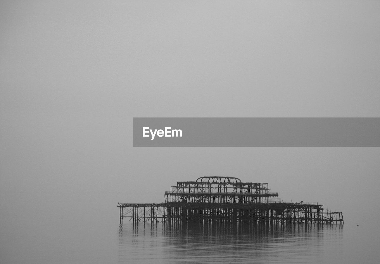 Pier in calm sea against clear sky