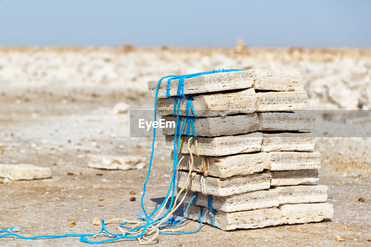 CLOSE-UP OF ROPE TIED ON SAND