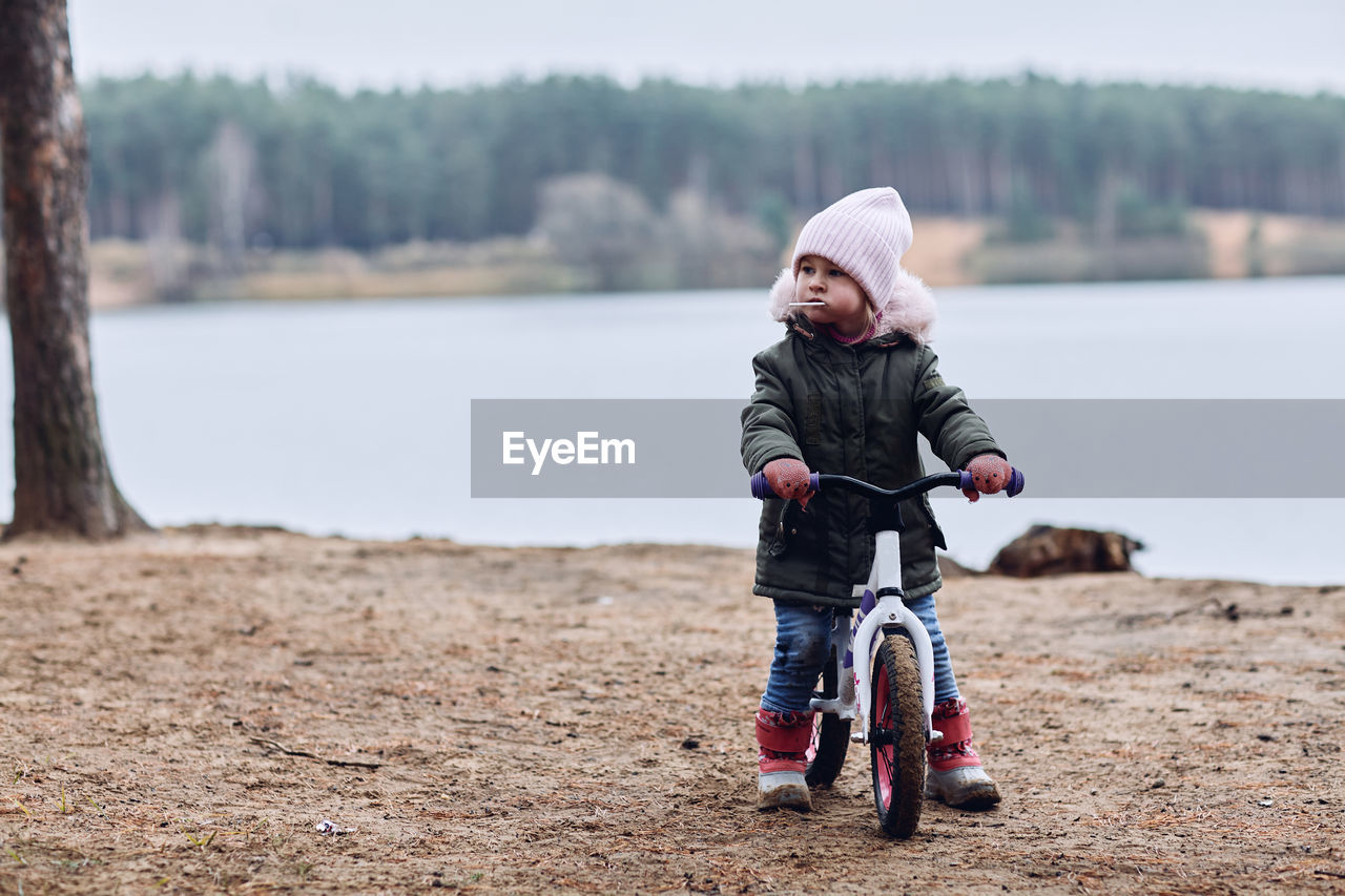 A little girl in the woods is driving on a running bike