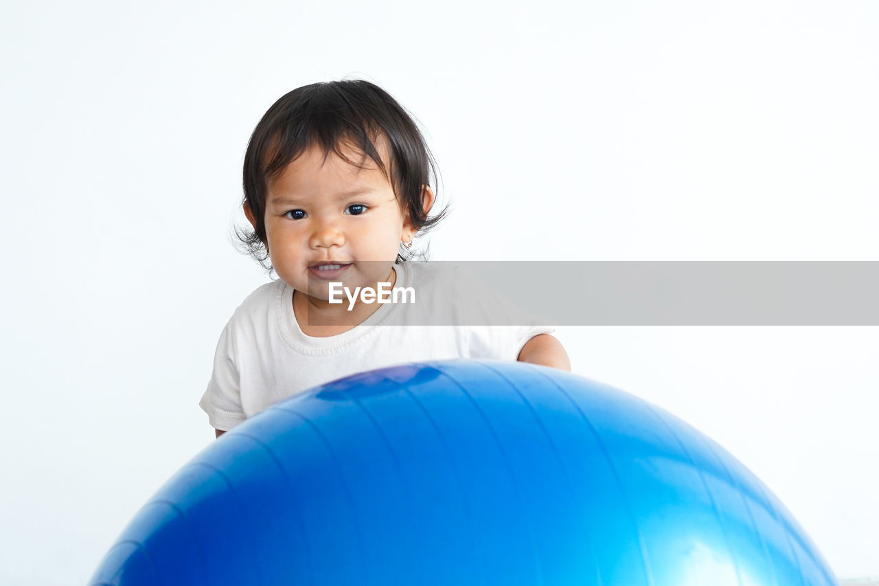 childhood, child, one person, portrait, happiness, smiling, person, toddler, emotion, looking at camera, cute, baby, inflatable, indoors, cheerful, clothing, copy space, men, white background, ball, blue, studio shot, fun, positive emotion, cut out, innocence, joy, black hair, lifestyles, headshot