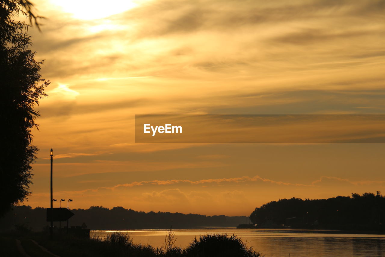 SCENIC VIEW OF LAKE AGAINST SKY AT SUNSET