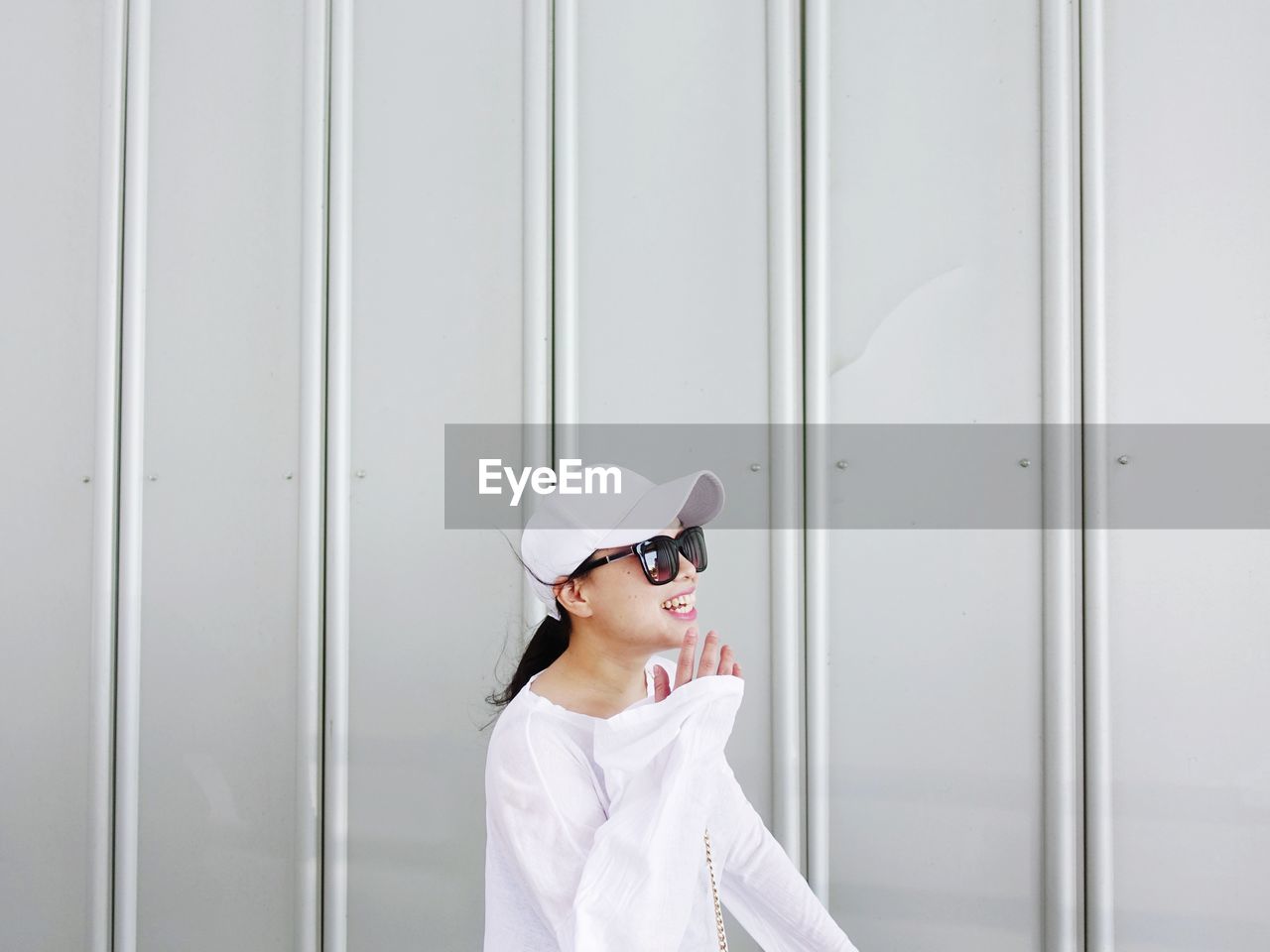 Smiling woman standing against white wall