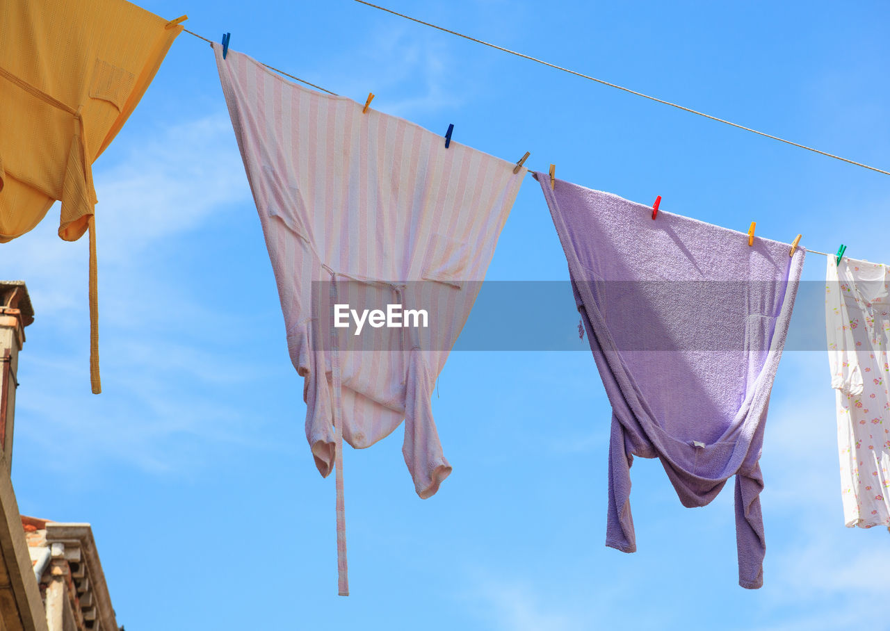low angle view of clothes drying on roof against clear blue sky