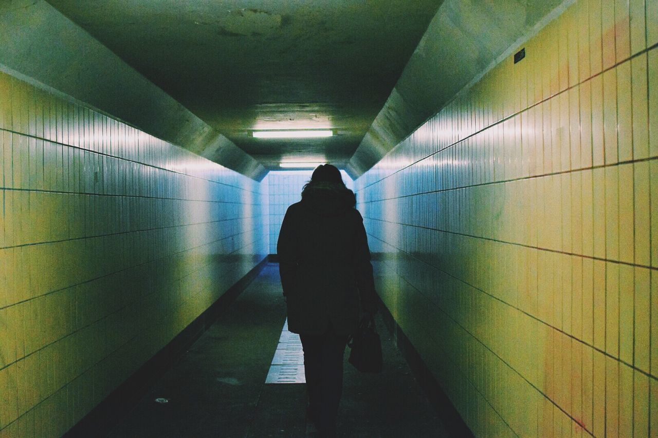 Rear view of silhouette person walking in tunnel