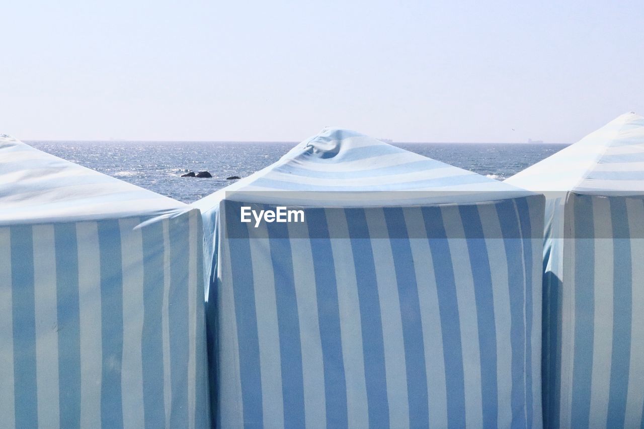 LOUNGE CHAIR ON BEACH AGAINST CLEAR SKY