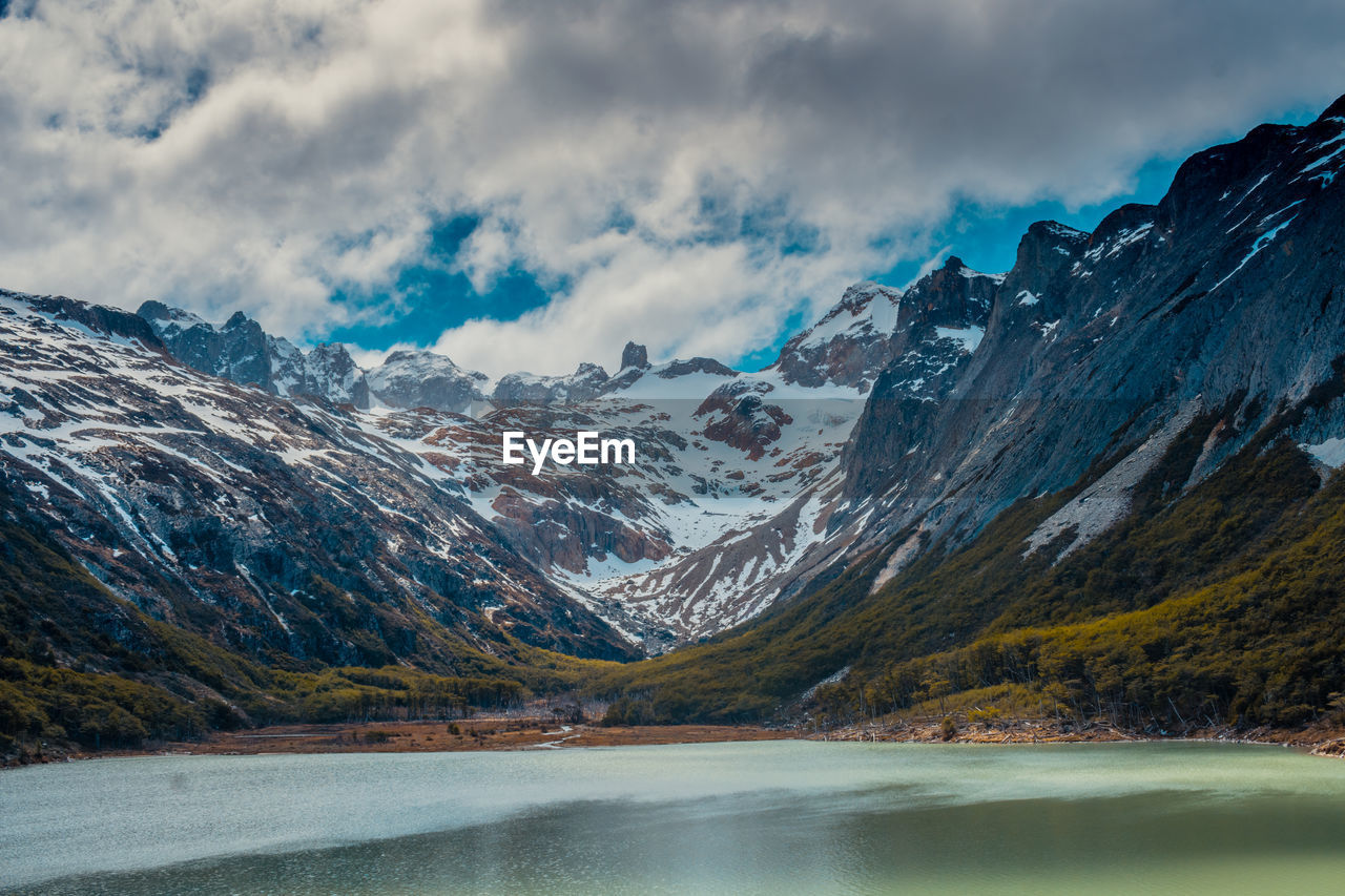 Scenic view of lake by snowcapped mountains against sky