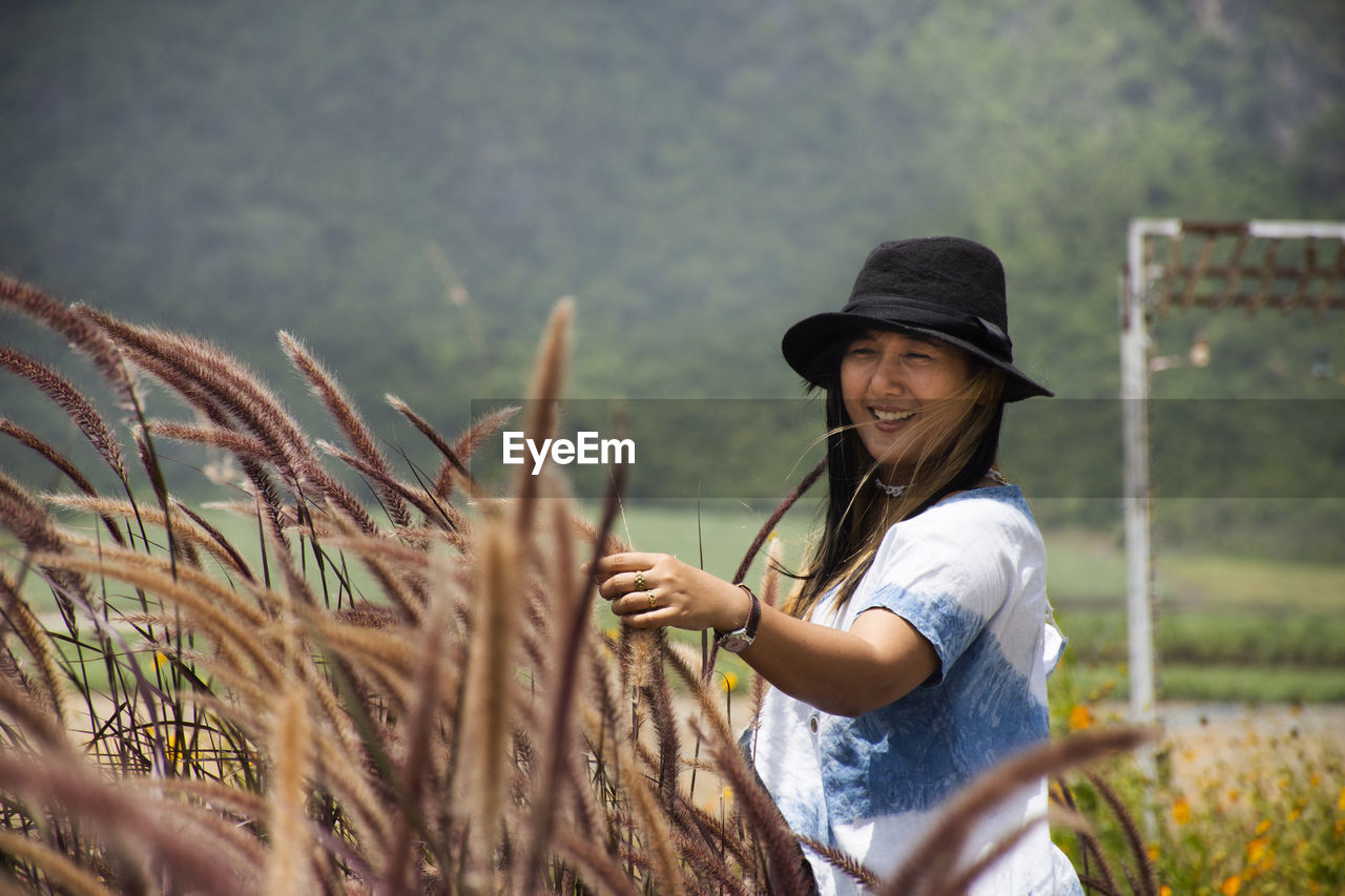 YOUNG WOMAN WEARING HAT STANDING ON LAND