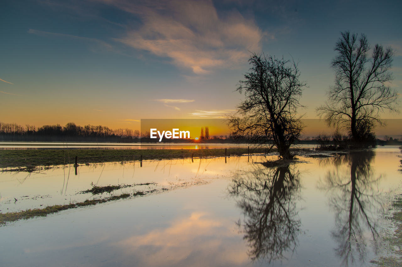 Scenic view of lake with silhouette trees reflection at sunset