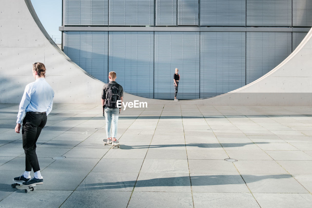 REAR VIEW OF PEOPLE WALKING ON FOOTPATH