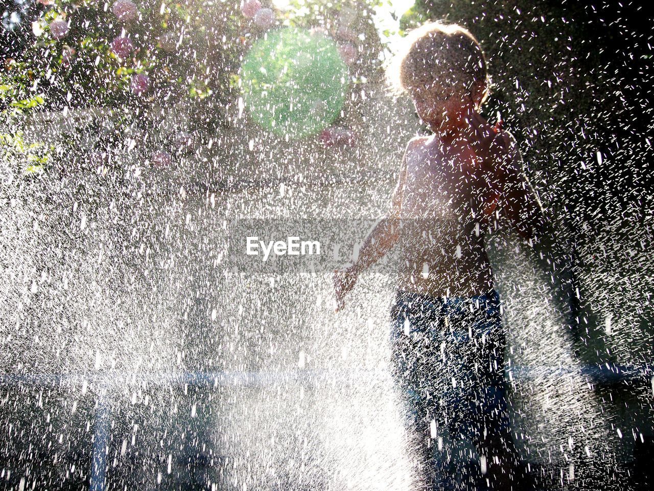 Boy enjoying water sprinkler in yard