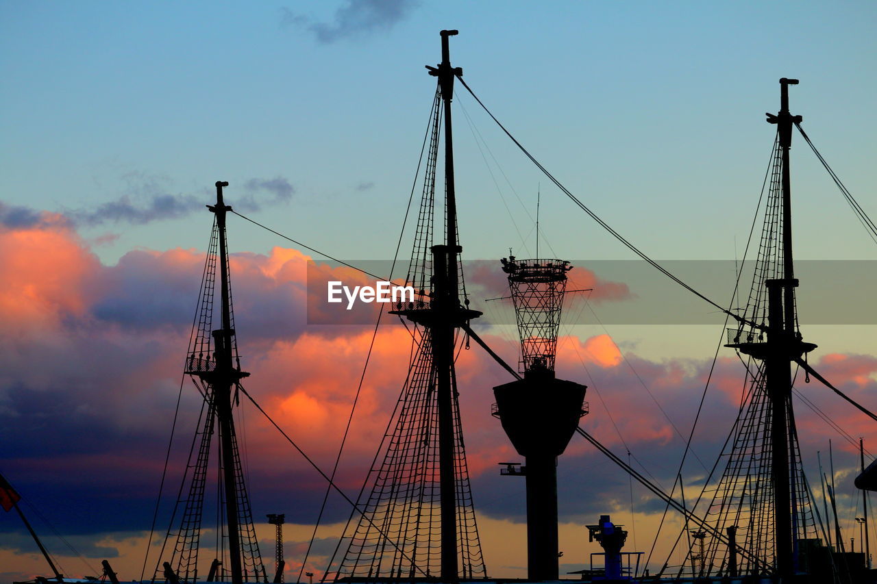 Low angle view of silhouette cranes against sky during sunset