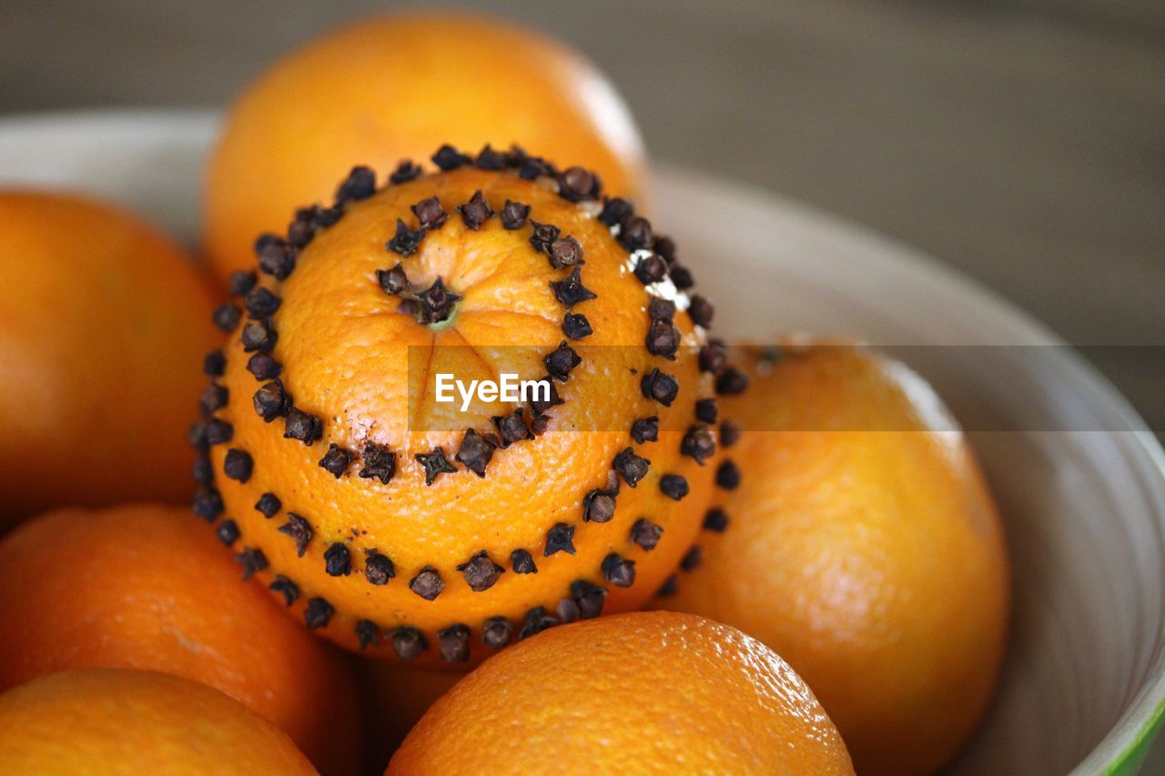 Close-up of oranges with cloves in bowl on table