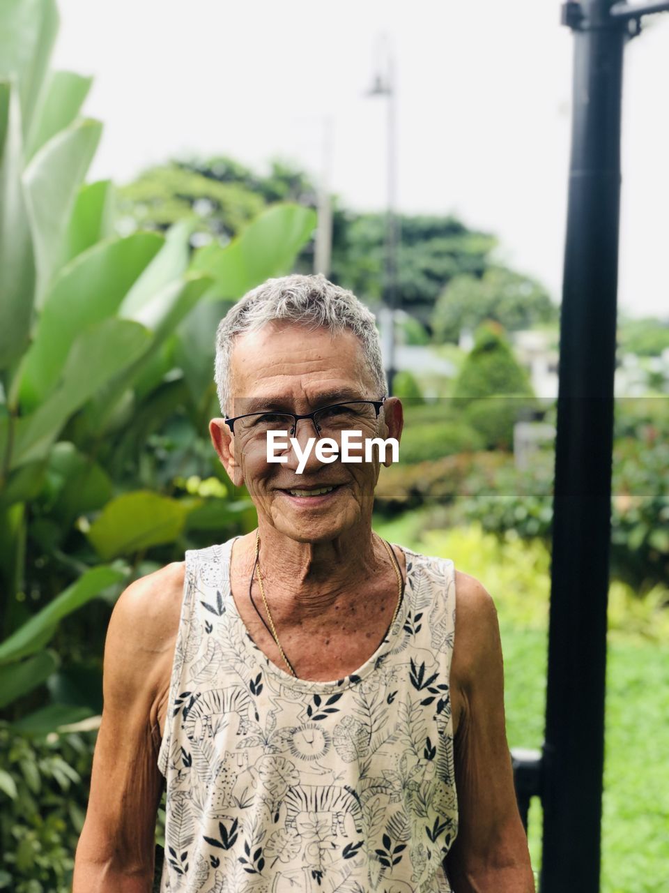 Portrait of old man standing outdoors against plants