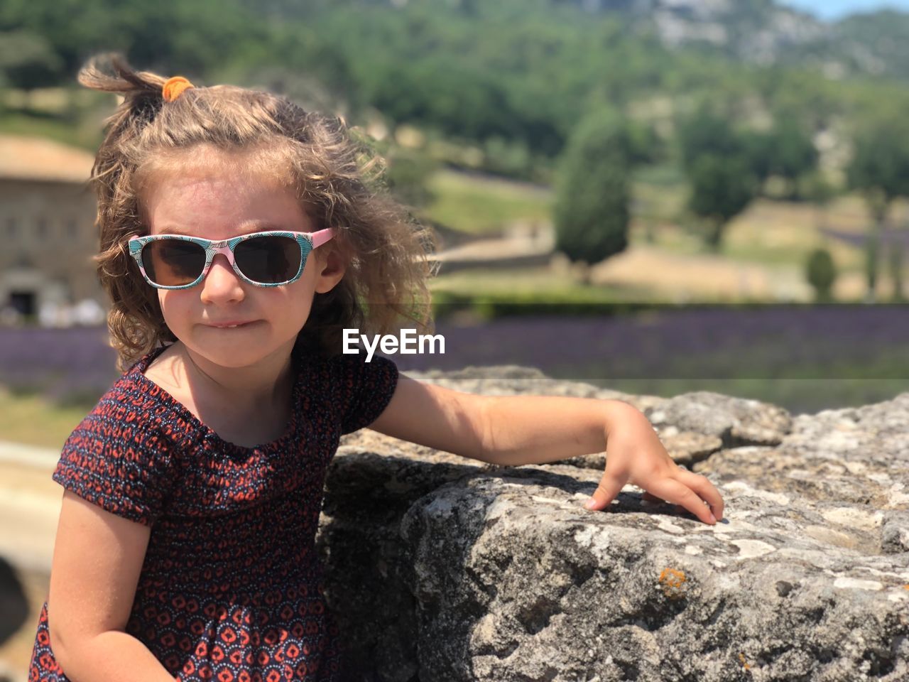 Portrait of girl wearing sunglasses while standing against rock