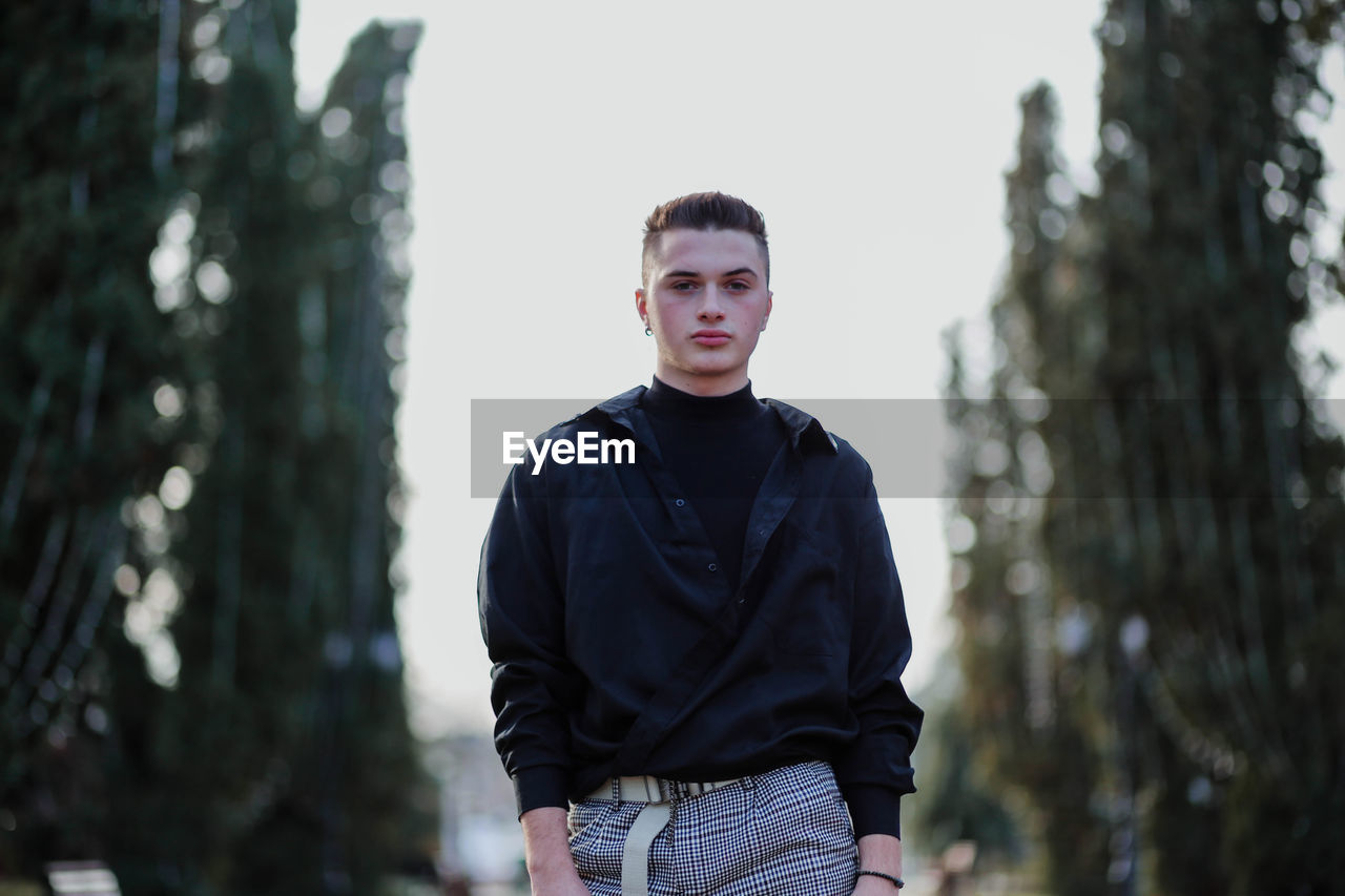 Portrait of young man standing against sky