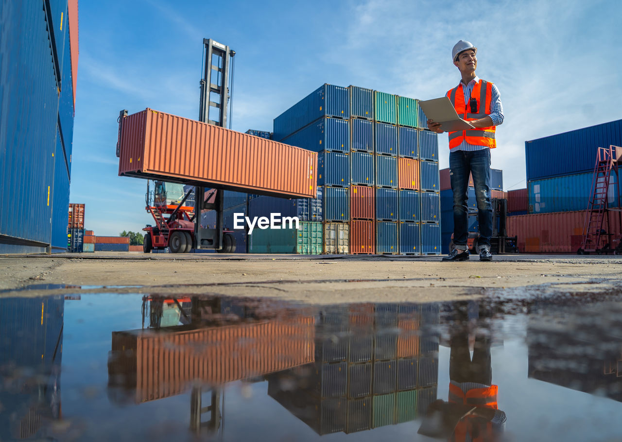 Engineers are overseeing the transportation of cargo with containers inside the warehouse. 