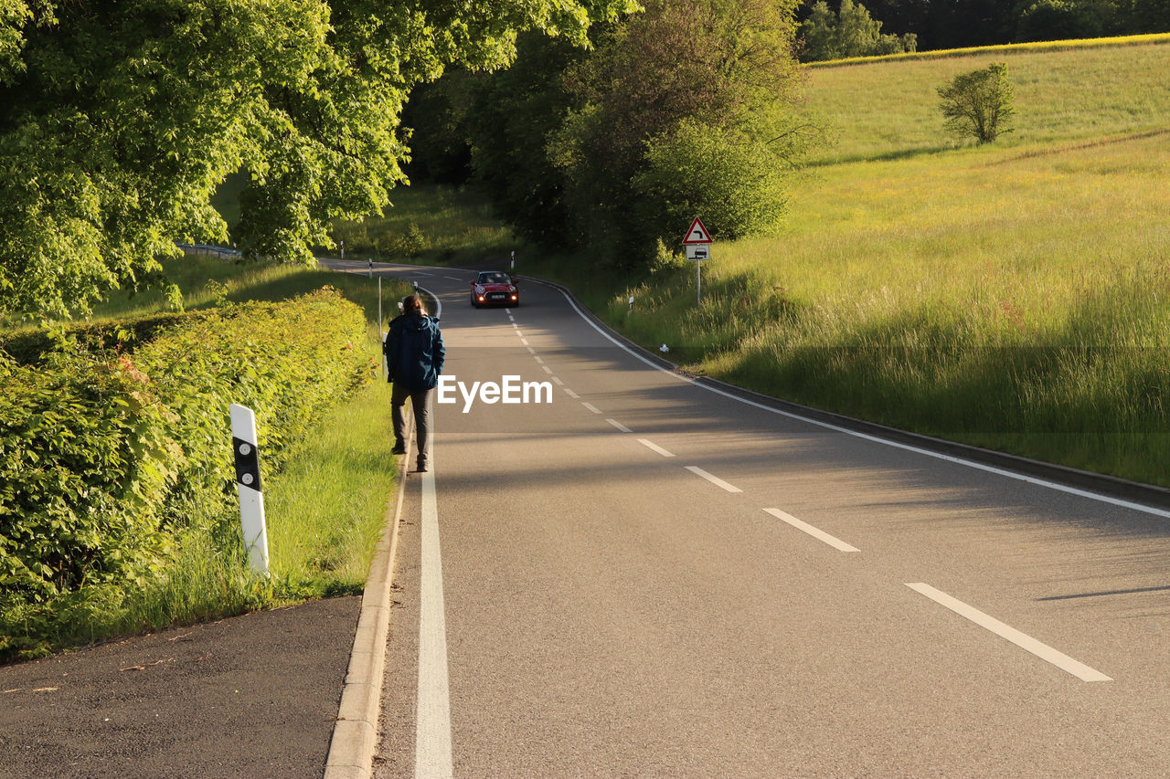 REAR VIEW OF PEOPLE WALKING ON ROAD