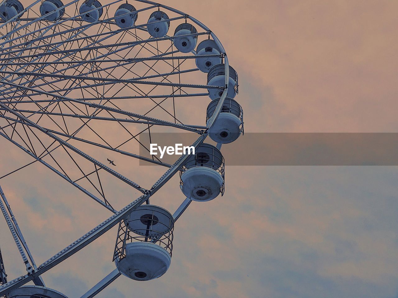 Low angle view of ferris wheel against cloudy sky during sunset