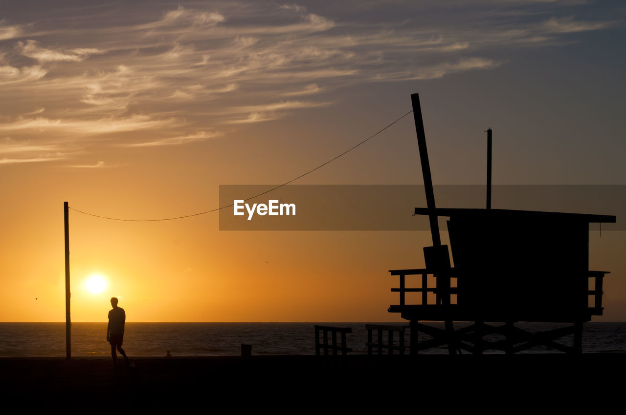 Silhouette man standing on pier against sky during sunset