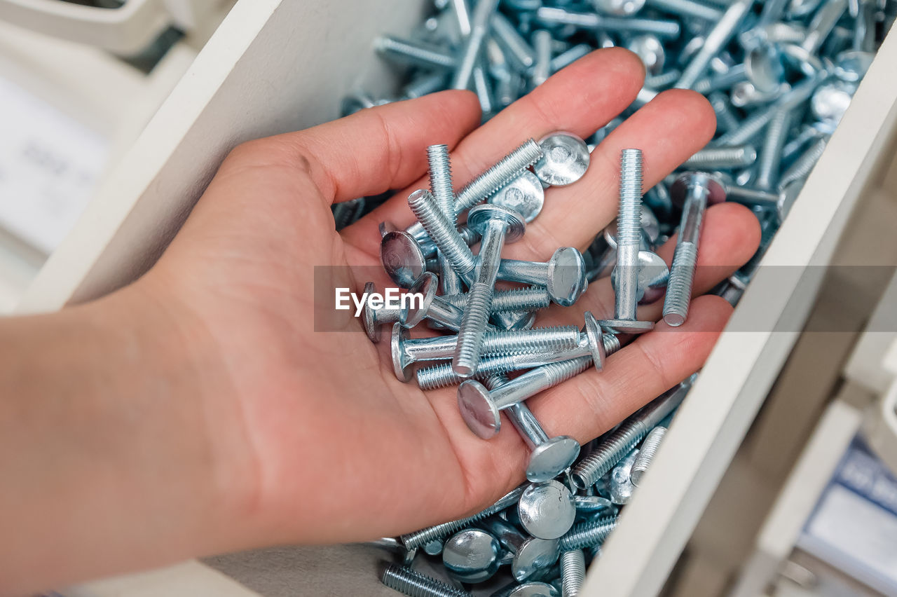 A lot of bolts in the palm of your hand. storage of screws in the store and at home