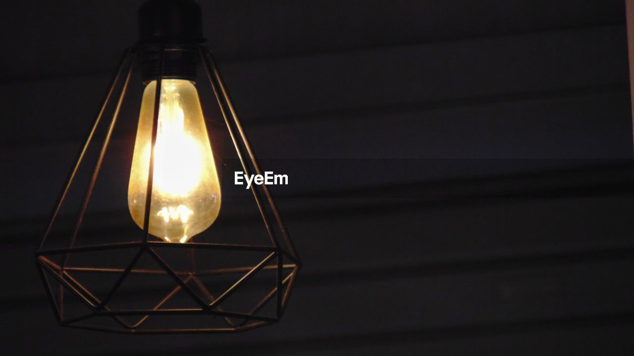 Close-up of illuminated light bulb against wall