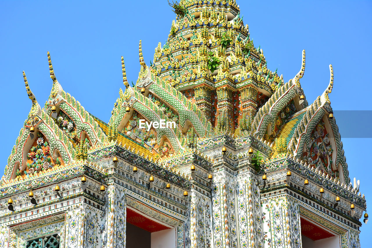 LOW ANGLE VIEW OF STATUE OF TEMPLE AGAINST BUILDING