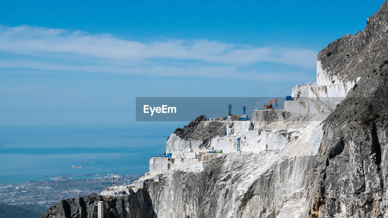 cliff, sky, sea, rock, terrain, nature, water, scenics - nature, coast, land, beauty in nature, mountain, vacation, beach, rock formation, travel destinations, travel, day, cloud, architecture, blue, mountain range, outdoors, ocean, environment, horizon, tranquil scene, non-urban scene, coastline, tourism, leisure activity, horizon over water, tranquility, landscape, built structure, geology, holiday, group of people, adventure, trip, idyllic