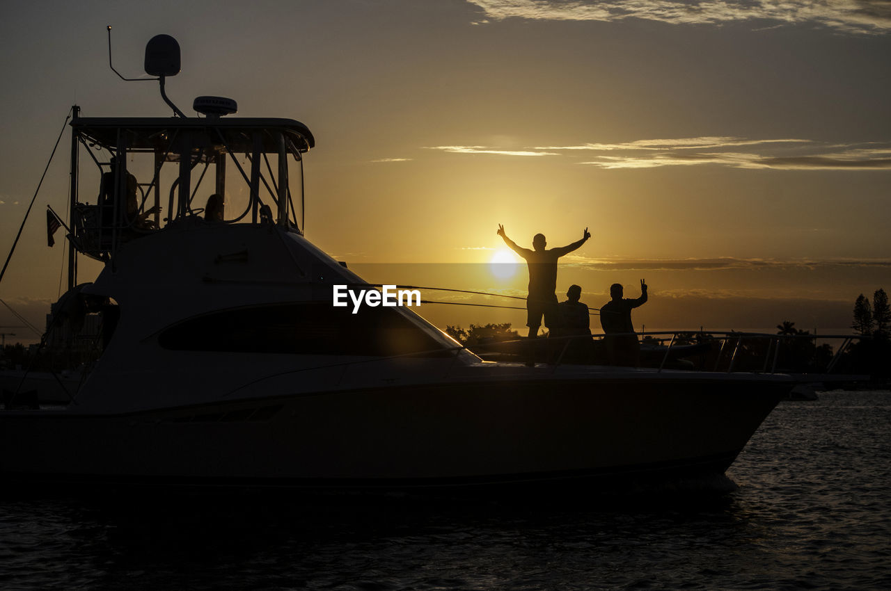 SILHOUETTE PEOPLE ON SAILBOAT AT SEA AGAINST SKY DURING SUNSET