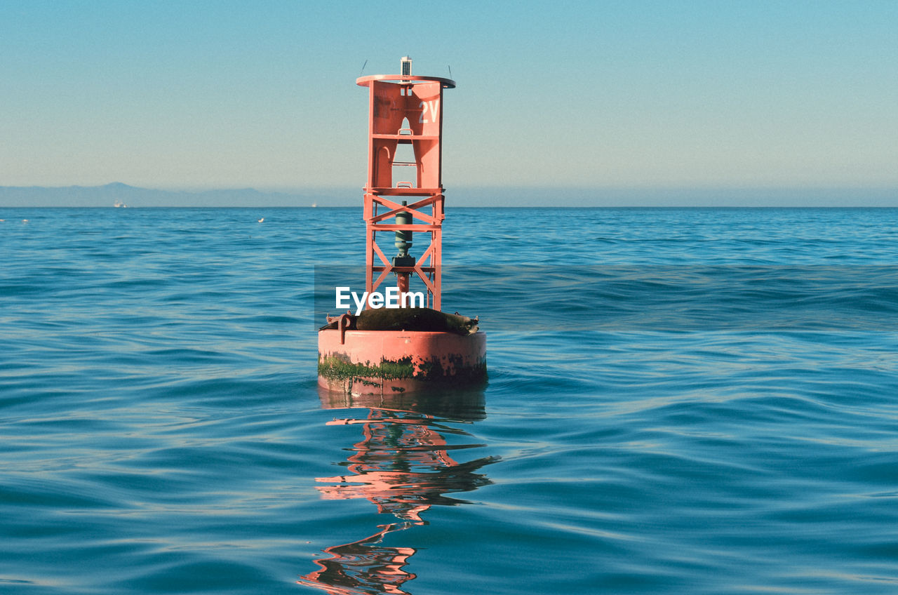 Buoy on sea against clear sky