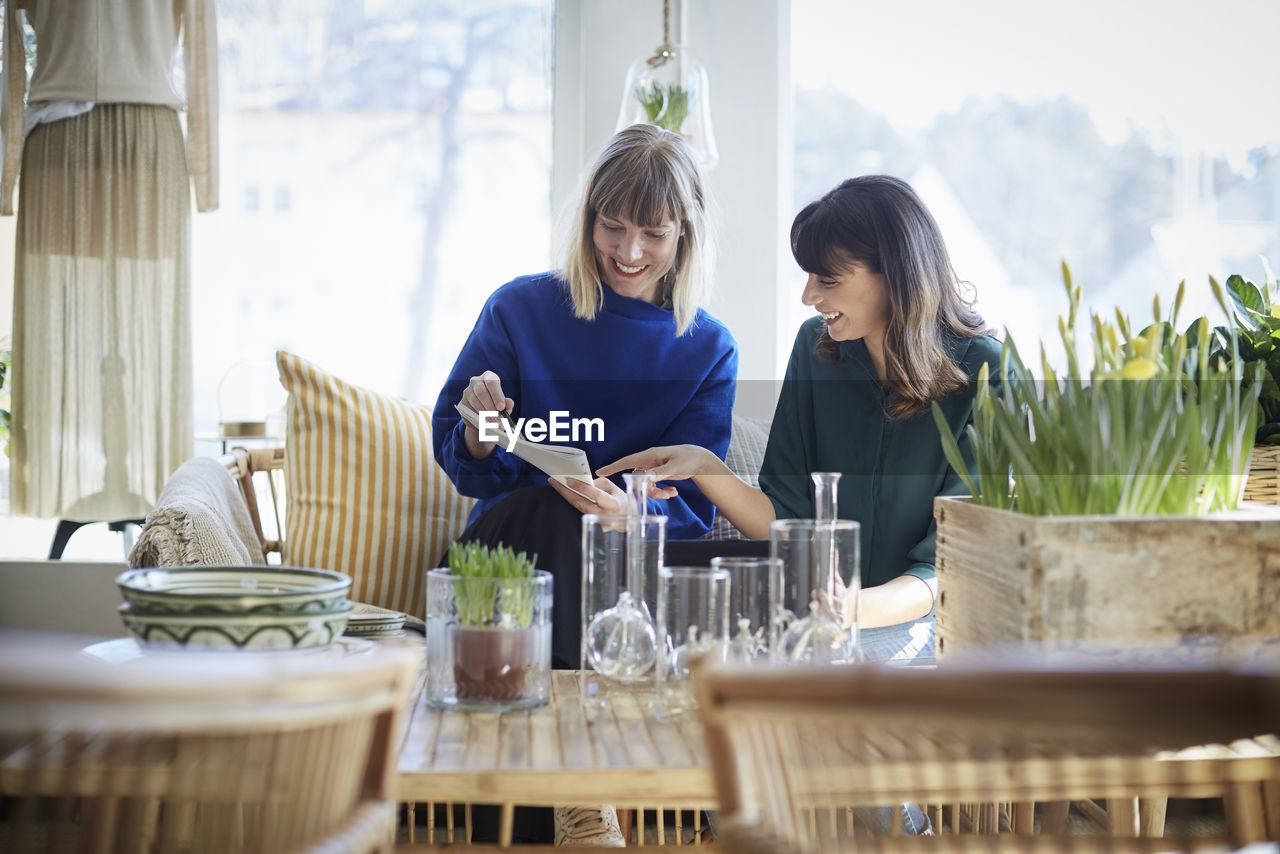 Smiling female owners discussing over documents at boutique