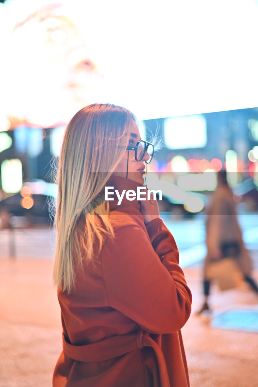 Portrait of young woman standing at night on street 