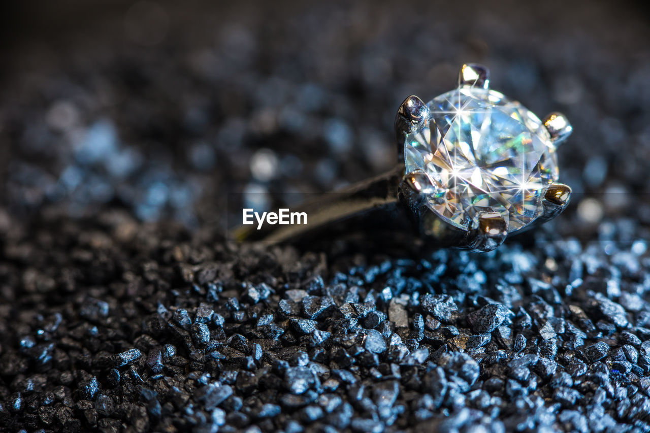 A ring with a cut gem lies on black sand