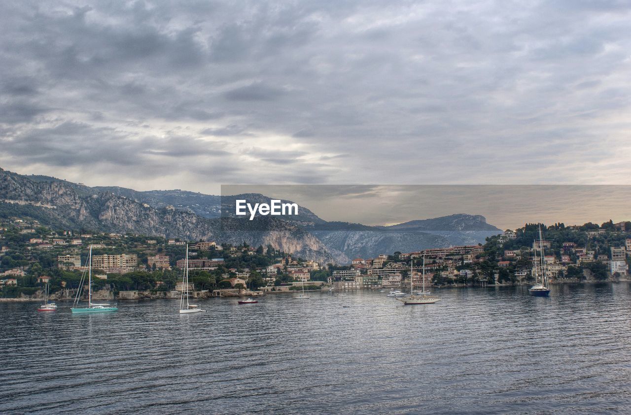 Residential district by river against cloudy sky