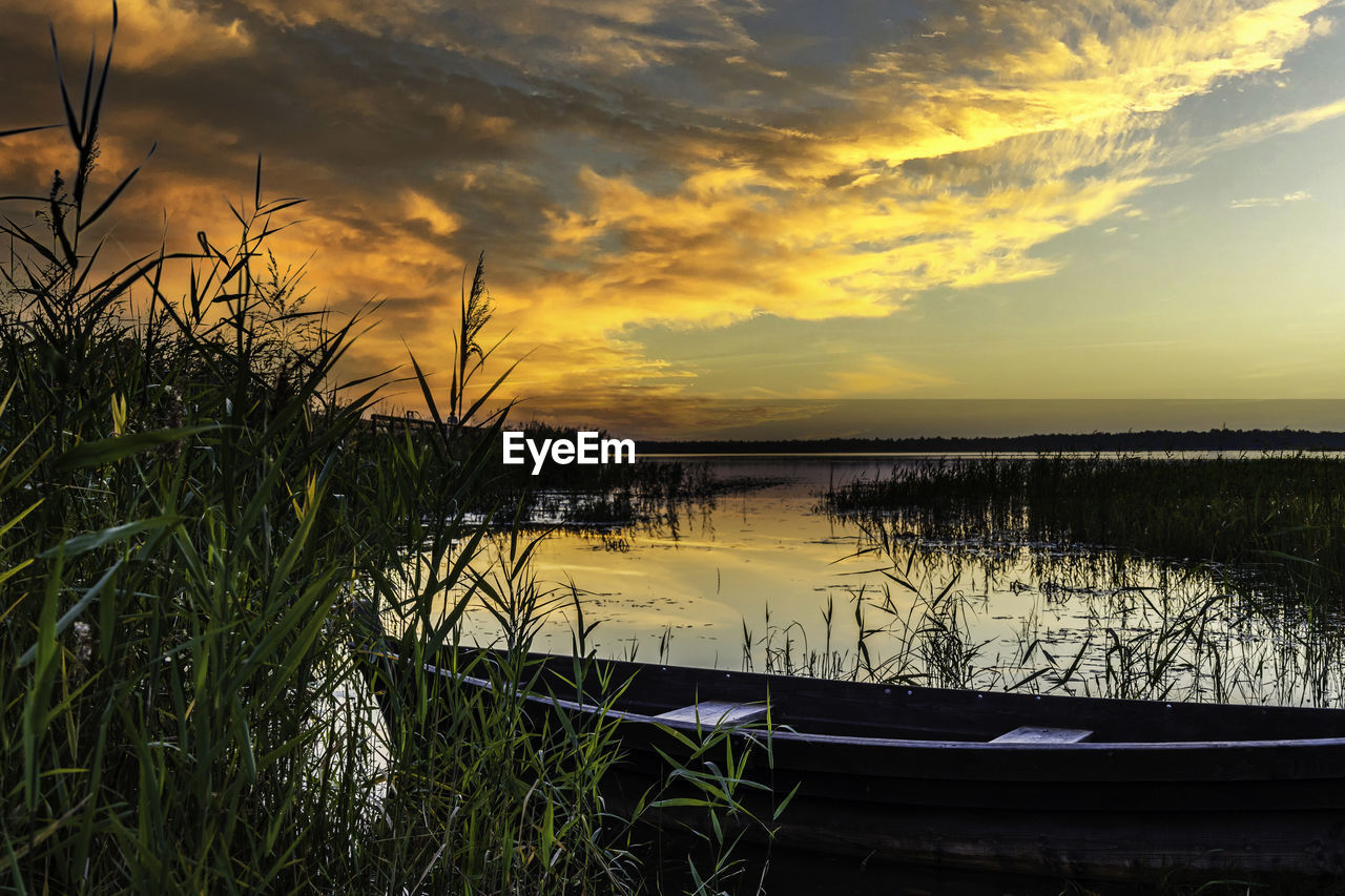 Old boat docked on a lake during golden sunset
