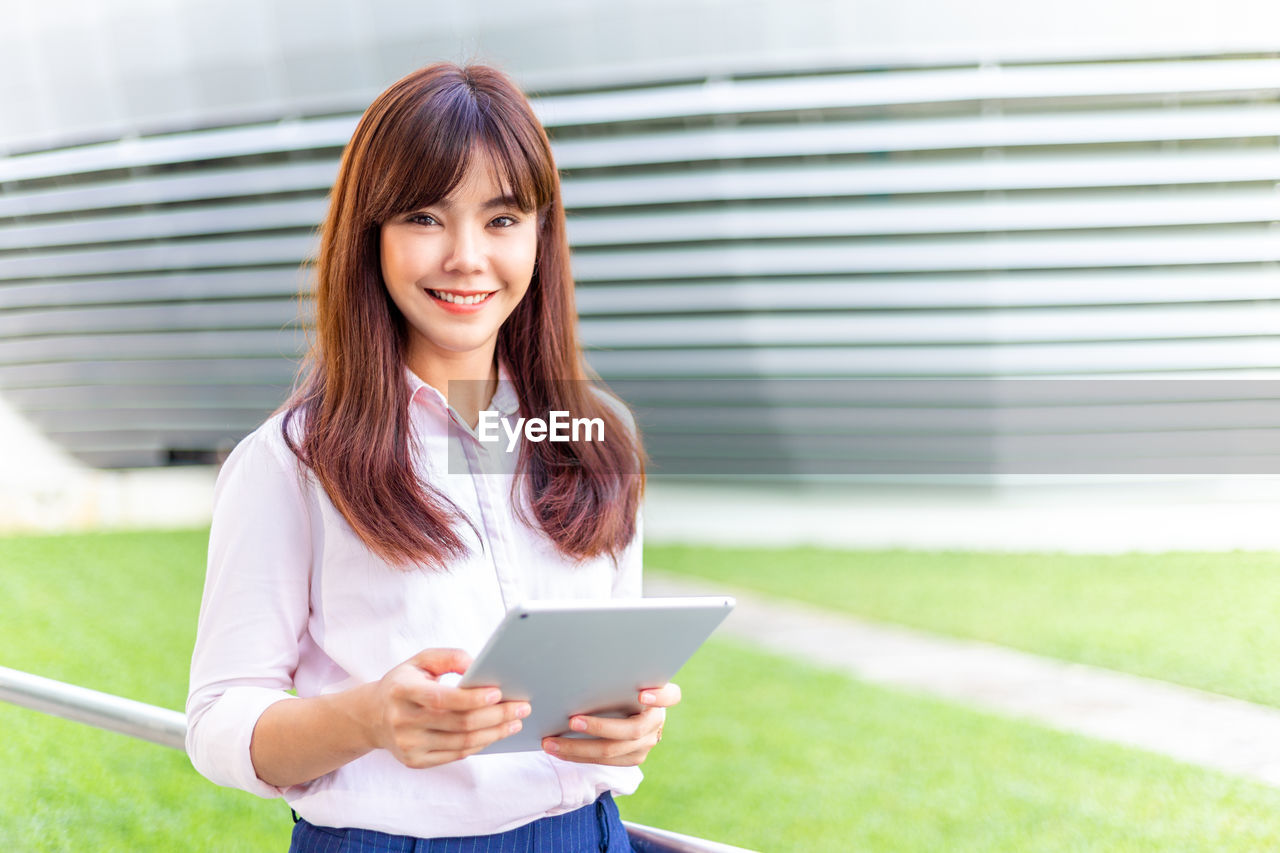 Happy young attractive business woman in her pink shirt using tablet computer to check social media