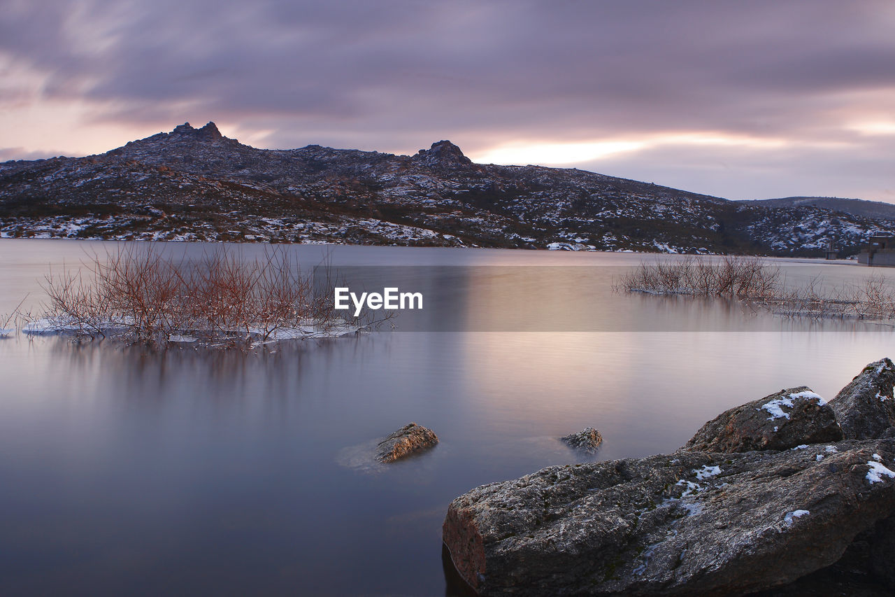 Scenic view of lake by snowcapped mountains against sky