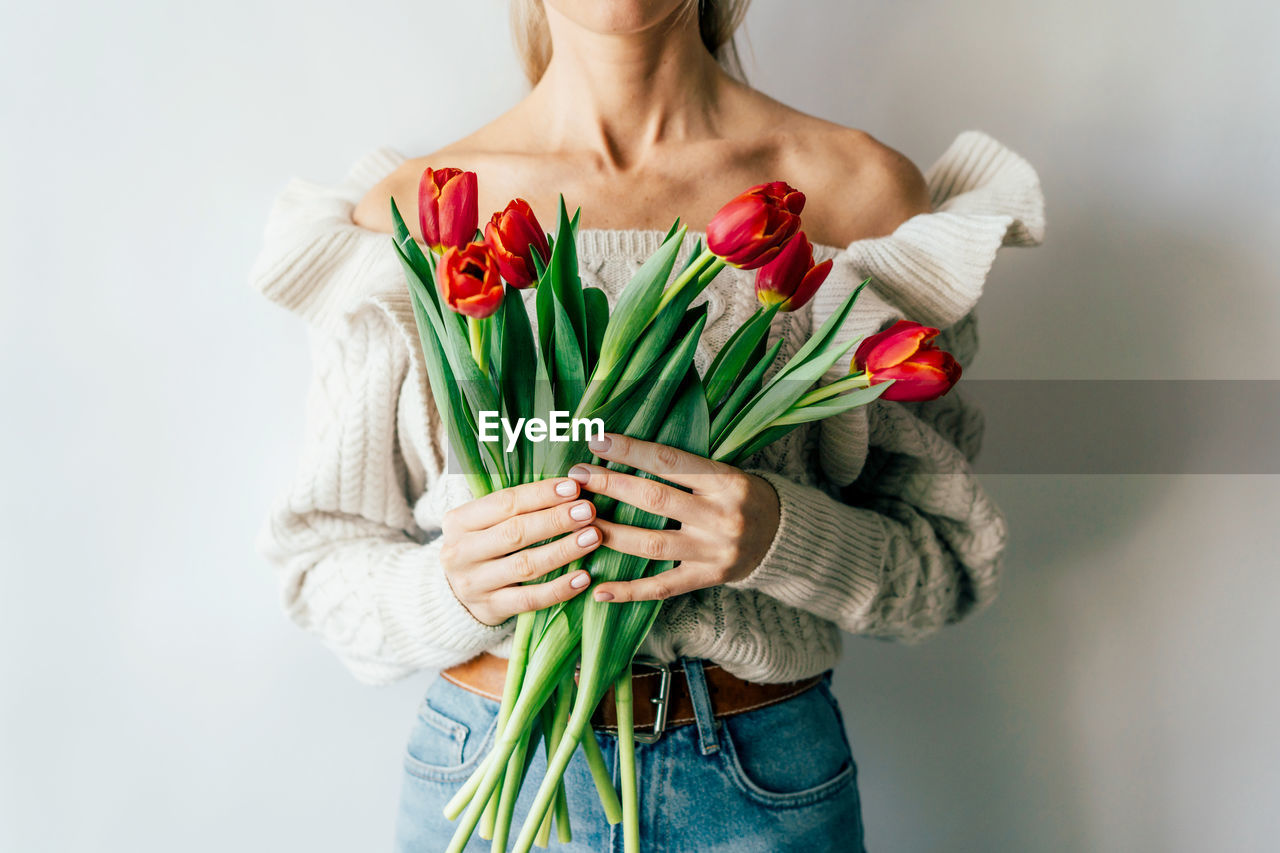 MIDSECTION OF WOMAN HOLDING RED FLOWER