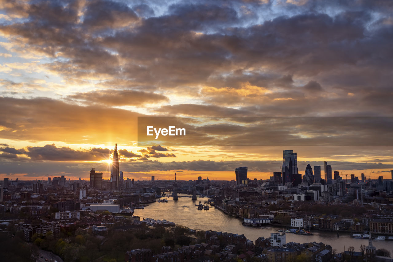 Buildings in city against cloudy sky during sunset