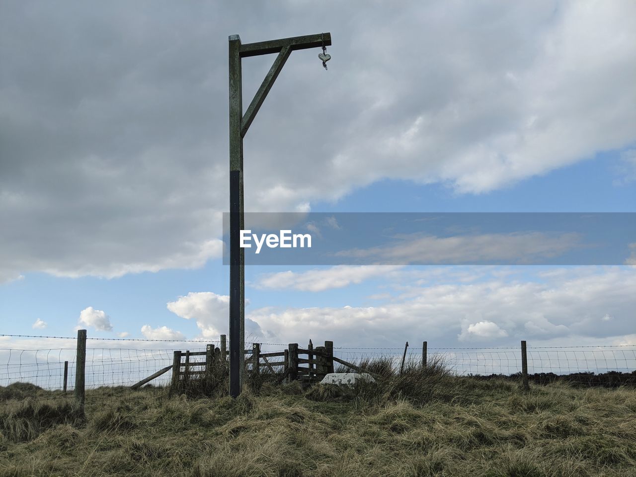 WOODEN POST ON FIELD AGAINST SKY