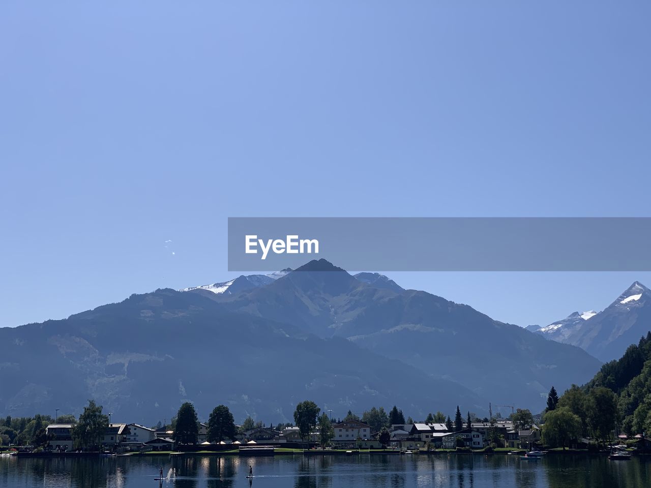 Lake by mountains against clear blue sky